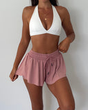 Person wearing a white sports bra and pink shorts on a plain background