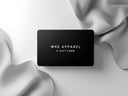 A black e-gift card from WRE Apparel laid on a silky grey surface.