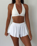 Woman wearing a white bikini set against a plain background