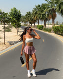 Woman walking on a road with palm trees and greenery in the background