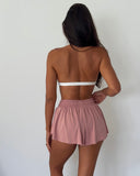Person wearing a white top and pink shorts on a plain background