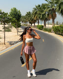 Woman walking on a road with palm trees and greenery in the background