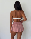 Person wearing a white top and pink shorts on a plain background