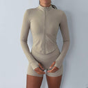 Beige activewear jacket with long sleeves and a zipper on a plain background