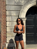 Woman in black athletic wear standing against a stone wall with a door.