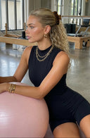Woman in a gym setting with exercise ball and Pilates reformer in the background